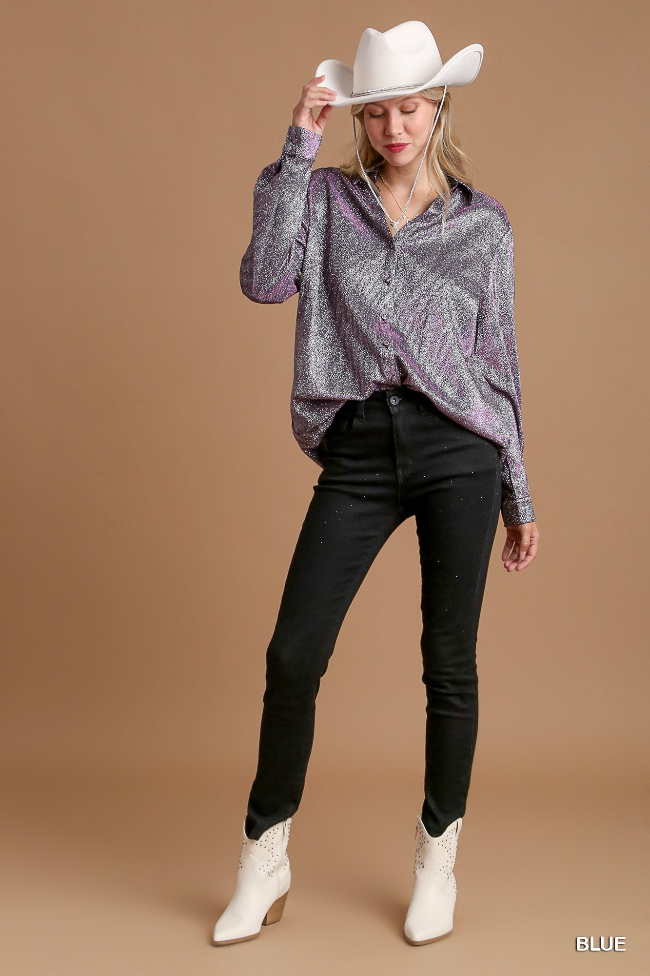 Woman wearing a patterned top, black pants, and white boots against a brown background