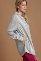 Woman wearing a silver long-sleeve top against a brown background