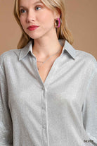 Woman wearing a silver shirt with a neutral background