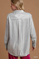 Woman wearing a silver metallic shirt against a brown background