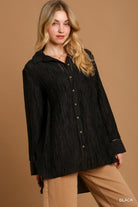 Woman wearing a black button up shirt against a brown background