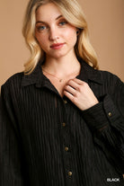 Woman wearing a black textured shirt against a beige background