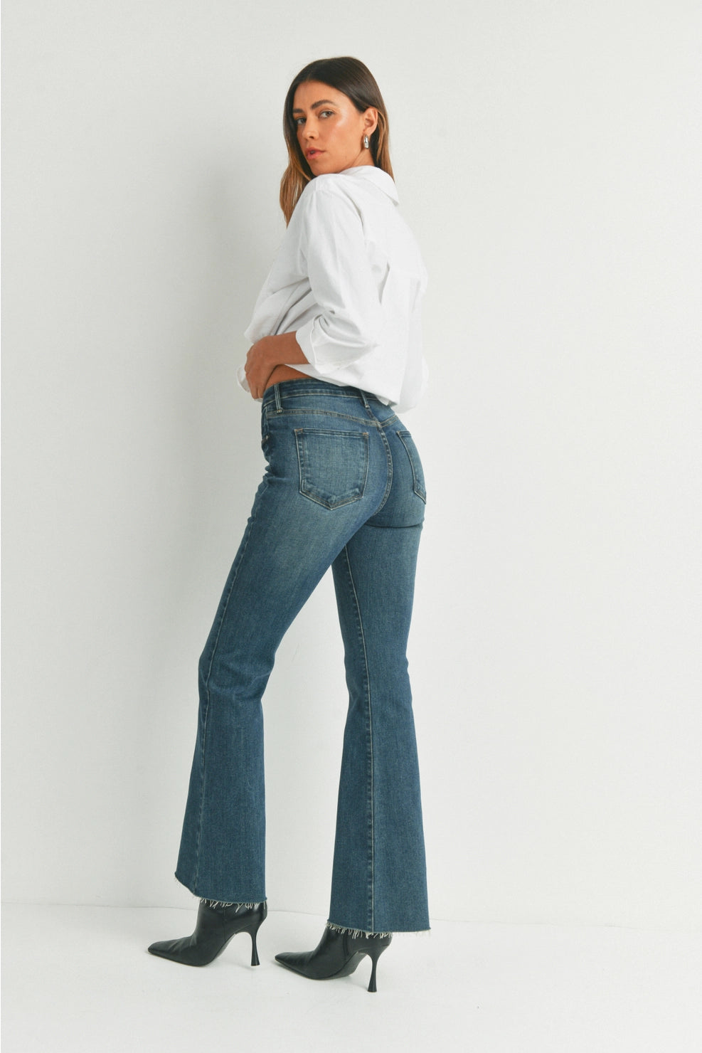 Woman wearing blue jeans and a white shirt on a white background