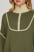 Green sweater with cream trim on a plain background