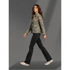 Woman wearing a camouflage jacket and black pants on a gray background