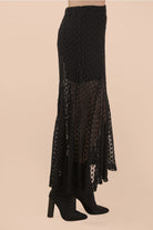 Black lace skirt with sheer panels on a beige background