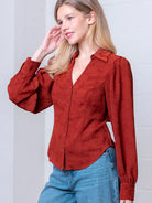 Front view of rust Western-inspired embossed blouse showing tailored waist and button front.