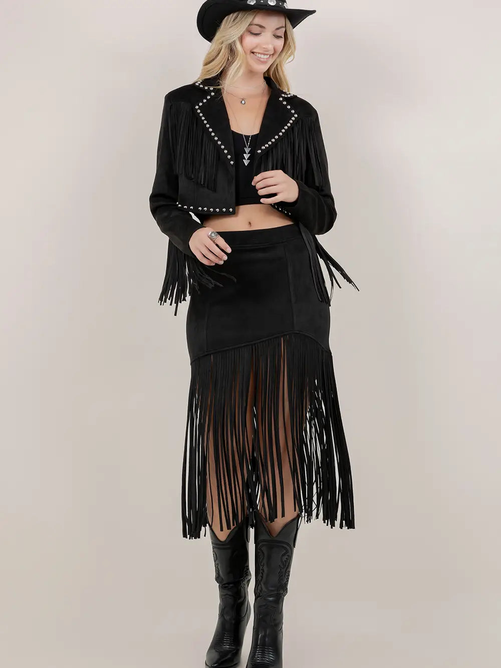Woman wearing a black fringe jacket and skirt with a plain background