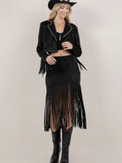 Woman wearing a black fringe jacket and skirt with a plain background