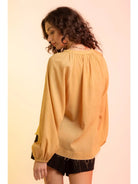 Back view: Back of yellow gauze blouse showing gathered neckline and elastic cuffs.