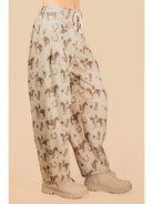 Light-colored pants with horse print worn by a person on a beige background