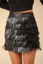 Close-up of tiered fringe and invisible side zipper on black vegan leather mini skirt