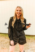 Woman in a black shirt and shorts outfit outdoors.