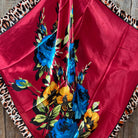 Red fabric with floral patterns and leopard print edges scarf on a wooden surface