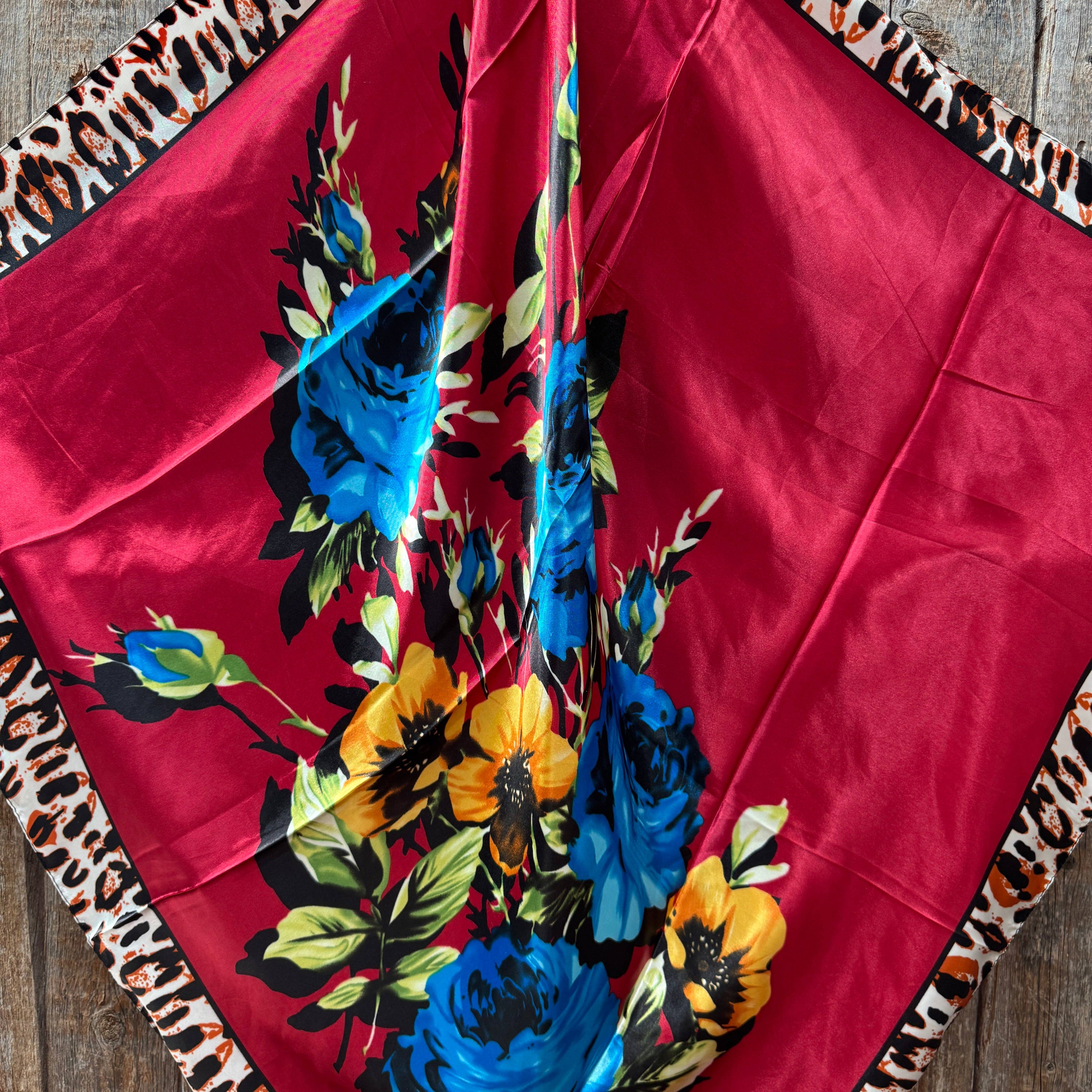 Red fabric with floral patterns and leopard print edges scarf on a wooden surface