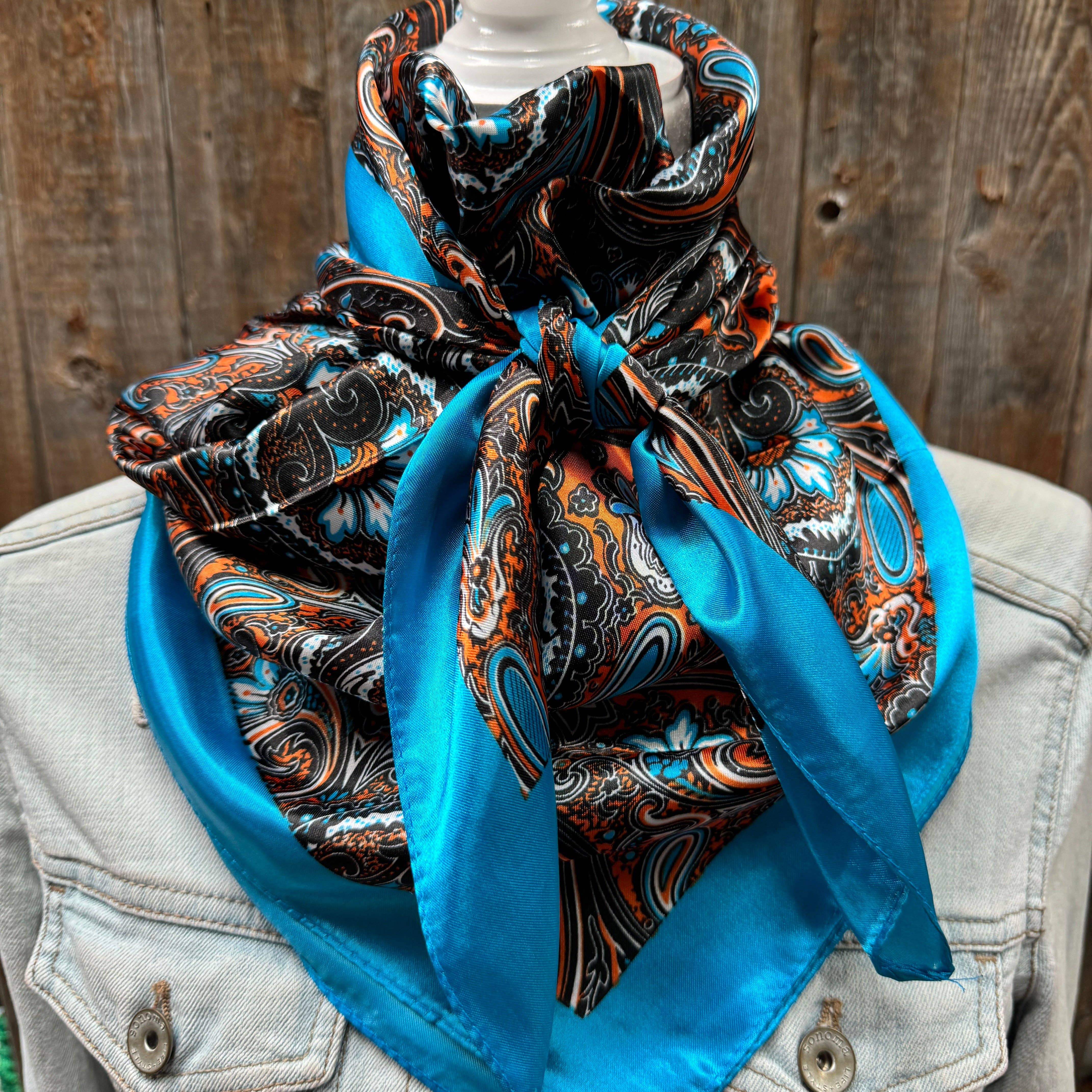 Blue  patterned scarf draped over a denim jacket against a wooden background