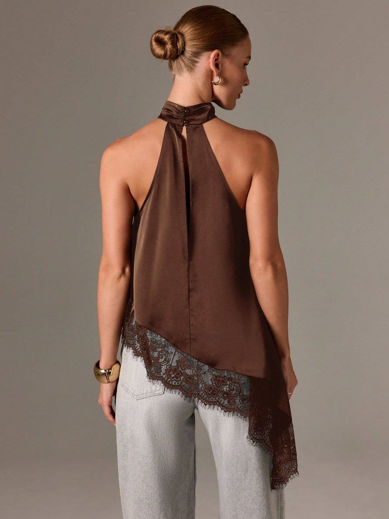 Woman wearing a brown halter top with lace trim on a plain background
