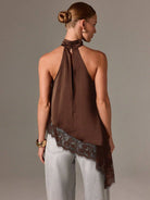 Woman wearing a brown halter top with lace trim on a plain background