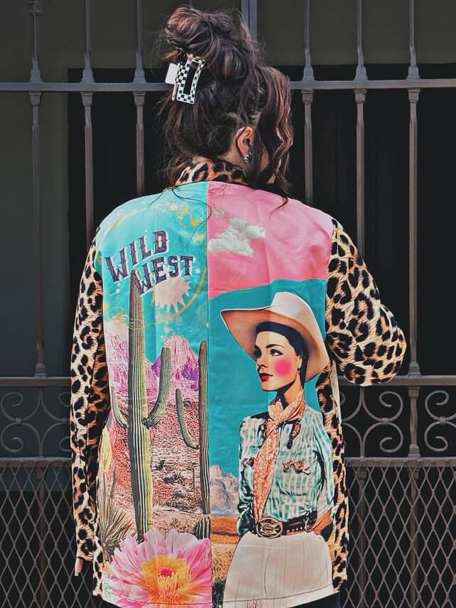 Colorful patchwork jacket with a cowboy design and 'Wild West' text, worn by a person.