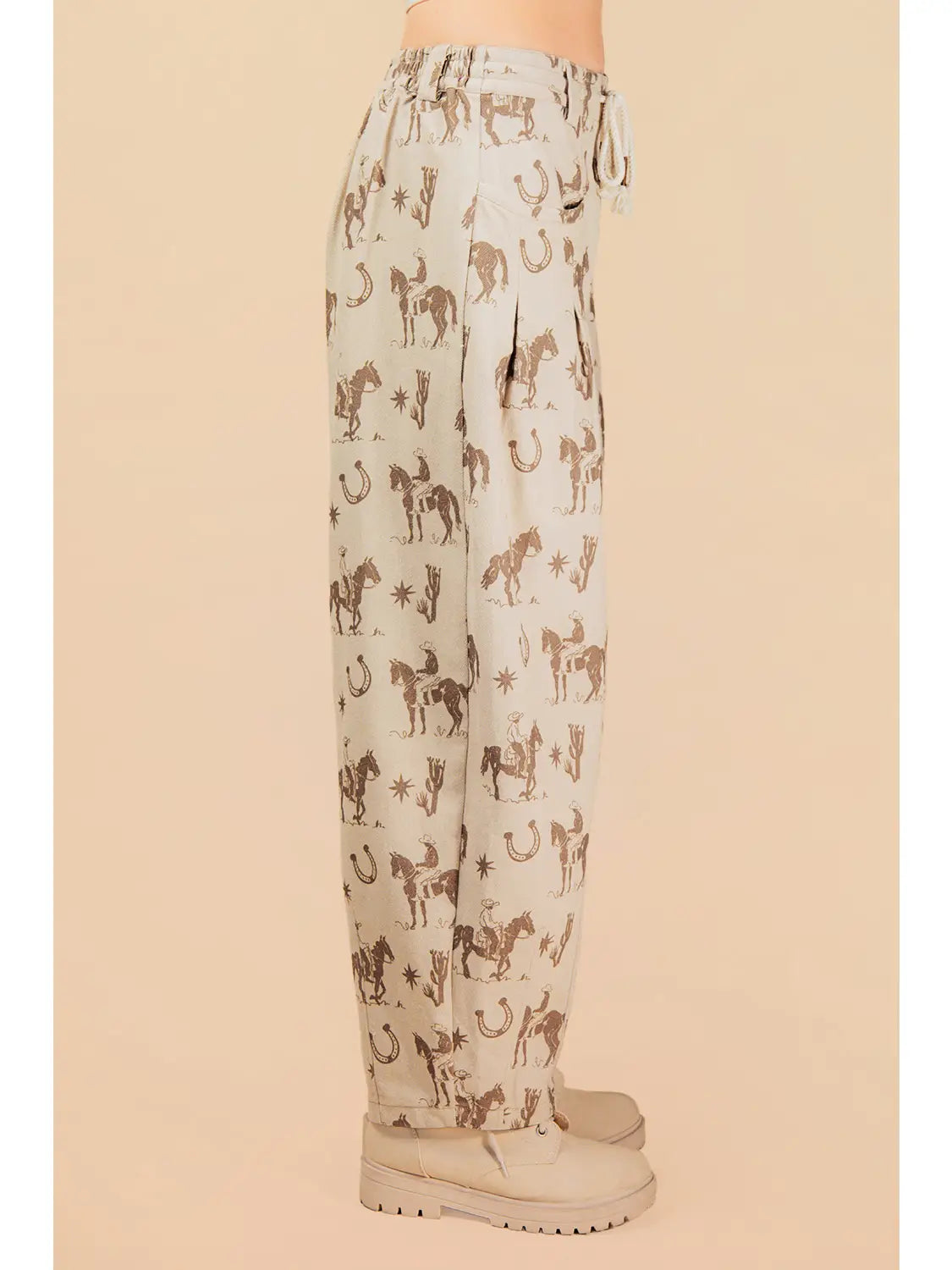 Light-colored pants with horse and horseshoe pattern worn by a person on a beige background