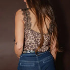 Person wearing a leopard print top with sheer back and high-waisted blue jeans against a dark background