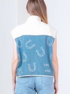 Model wearing indigo denim vest with white horseshoe print and faux-fur collar, zipped front, hands in pockets.”