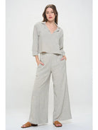 Light gray pin stripped pants worn with elastic  waist by a person 