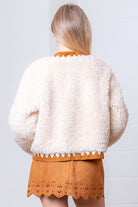 Back of cream faux-fur jacket showing suede-contrast hem, cuffs, and collar.