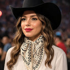 Woman wearing a black cowboy hat and a patterned scarf in a blurred crowd setting