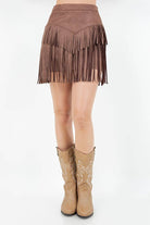 Brown fringe skirt worn with tan cowboy boots on a white background