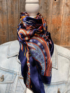 Patterned scarf draped over a denim jacket against a wooden background