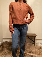 Person wearing a brown faux leather button up jacket and blue jeans 