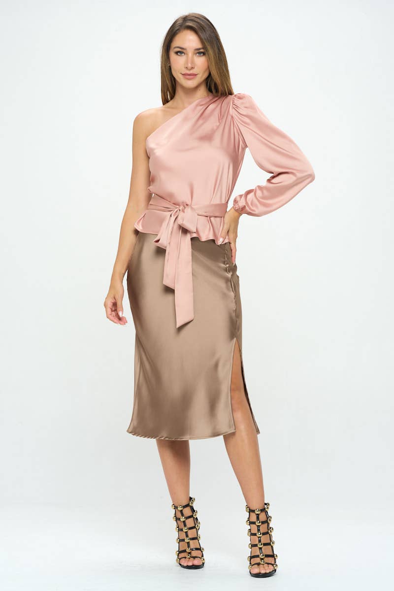 Woman wearing a pink one-shoulder top and beige skirt on a white background