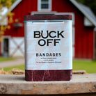 Can of Buck Off bandages with a barn in the background