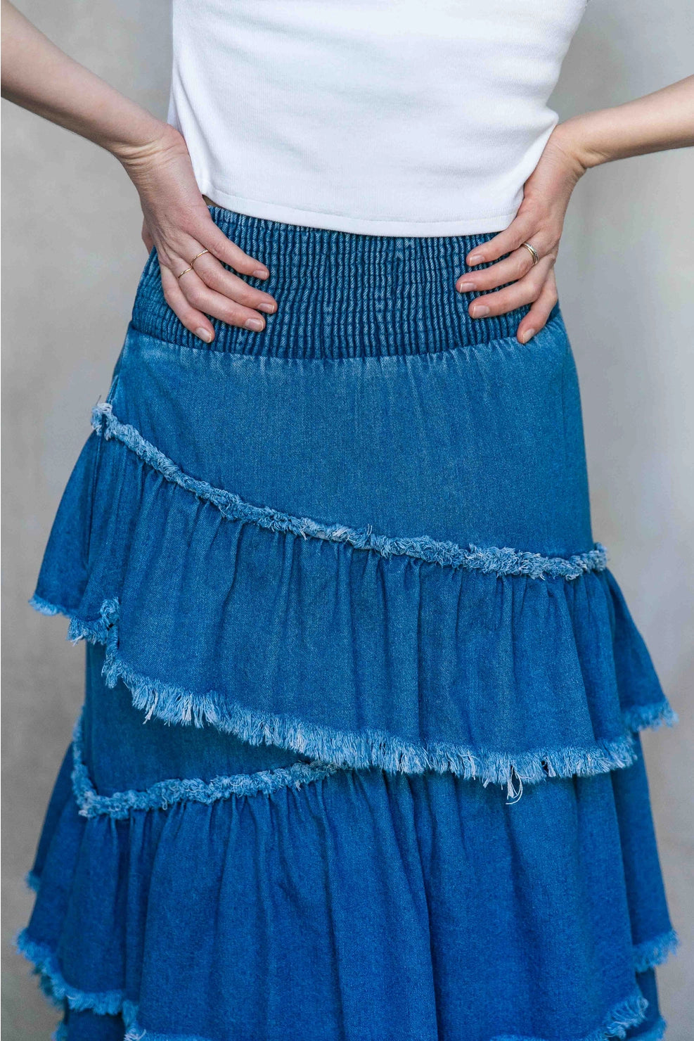 Blue tiered skirt worn by a person against a neutral background