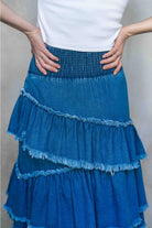 Blue tiered skirt worn by a person against a neutral background