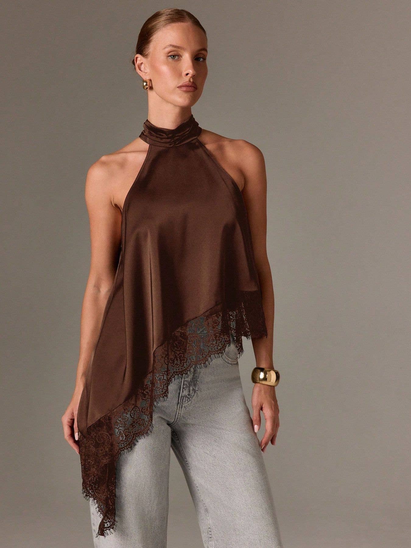 Woman wearing a brown halter top with lace details on a plain background