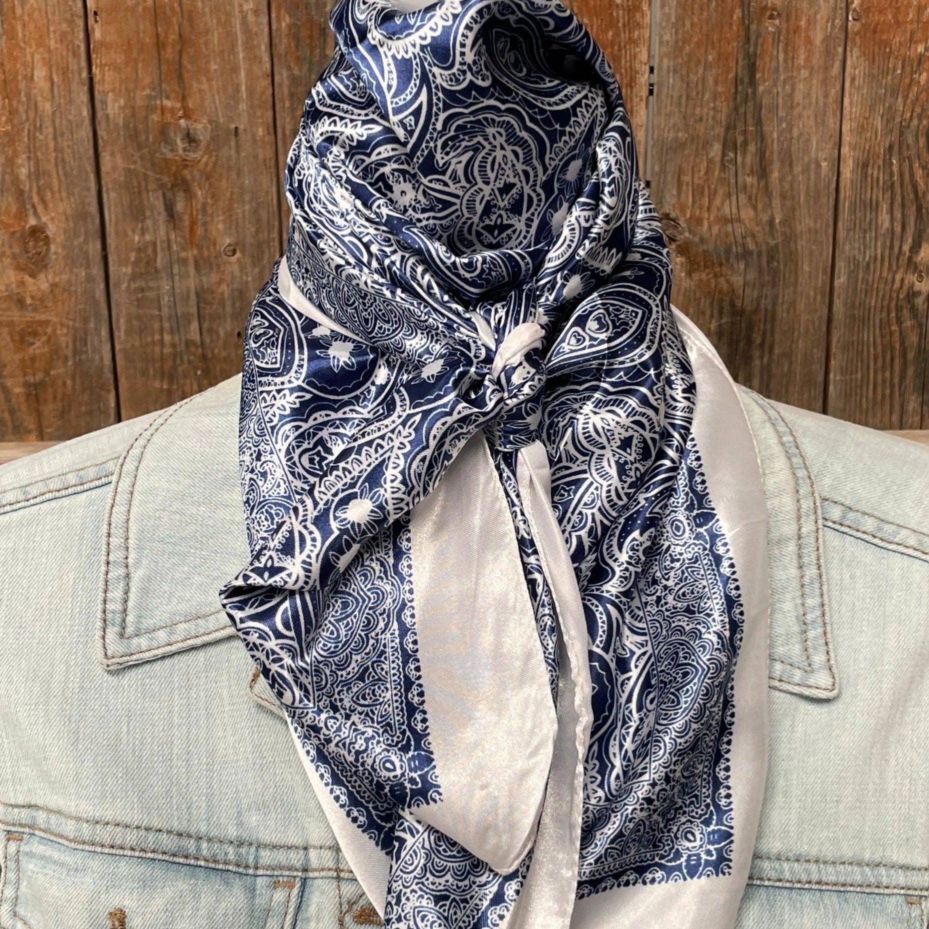 Navy paisley scarf draped over a light-colored jacket against a wooden background