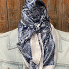Navy paisley scarf draped over a light-colored jacket against a wooden background