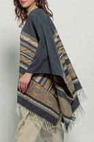 Dark gray poncho with brown and beige striped pattern and fringes on a white background