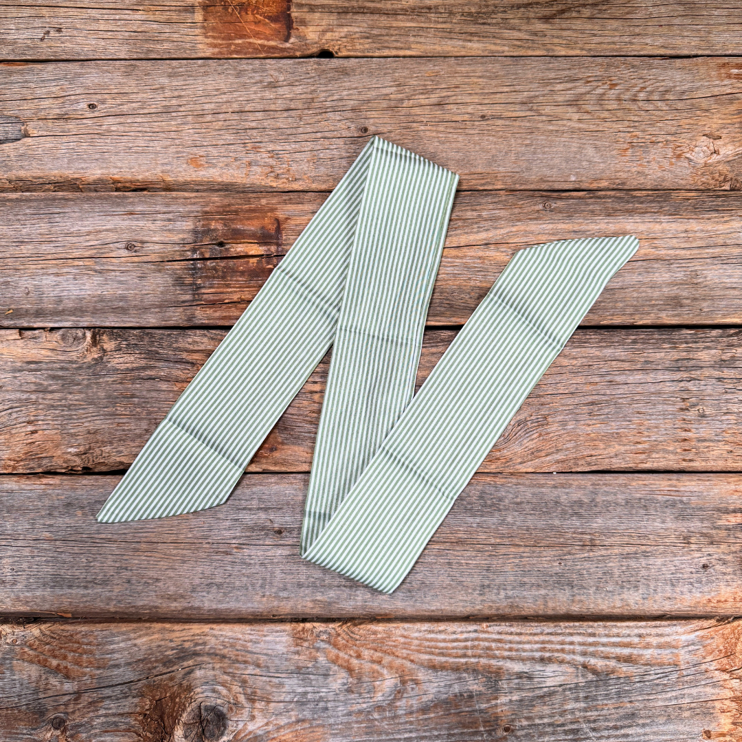 Two green striped ribbons on a wooden surface