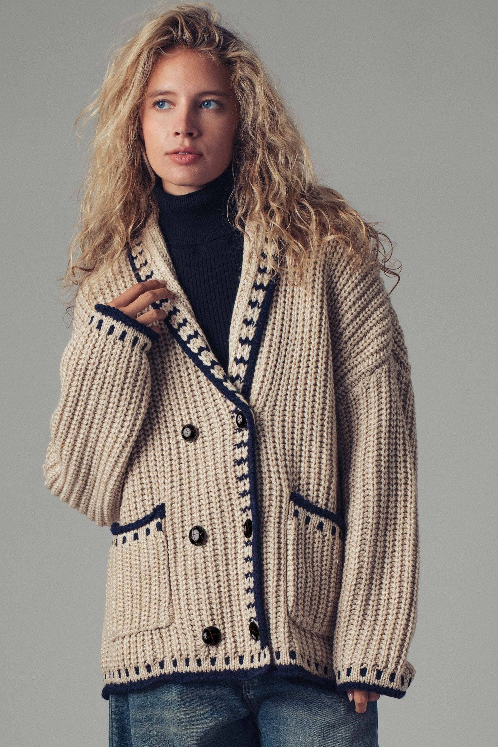 Woman wearing a beige knitted cardigan with black buttons on a gray background