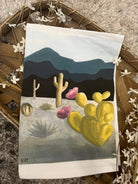 Painting of a desert scene with cacti on a white tea towel.