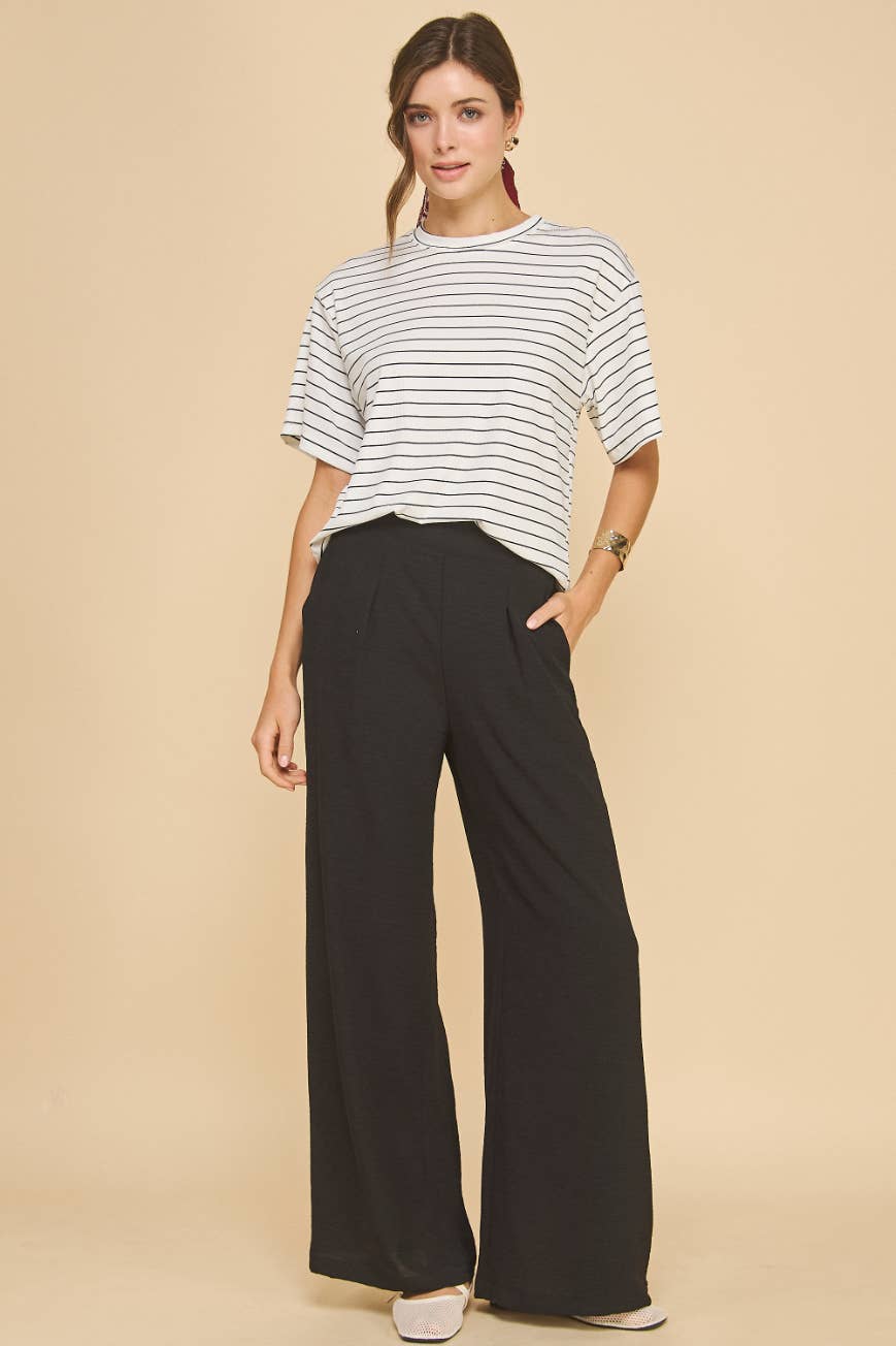 Woman wearing a striped shirt and black wide-leg pants on a beige background