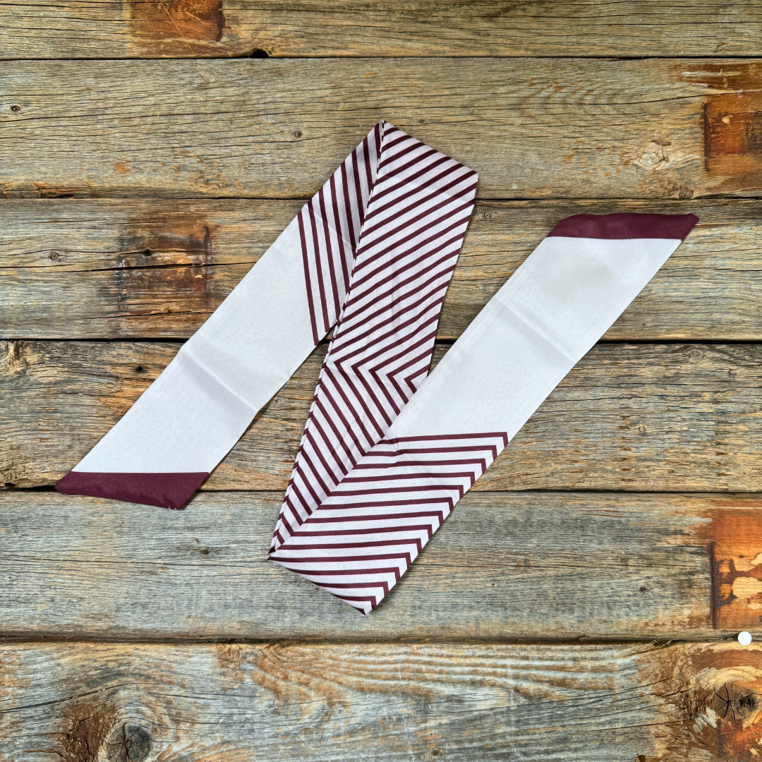 Burgundy and cream striped thin scarf on a wooden surface.