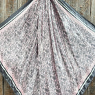 Patterned pink and grey fabric scarf on a wooden surface