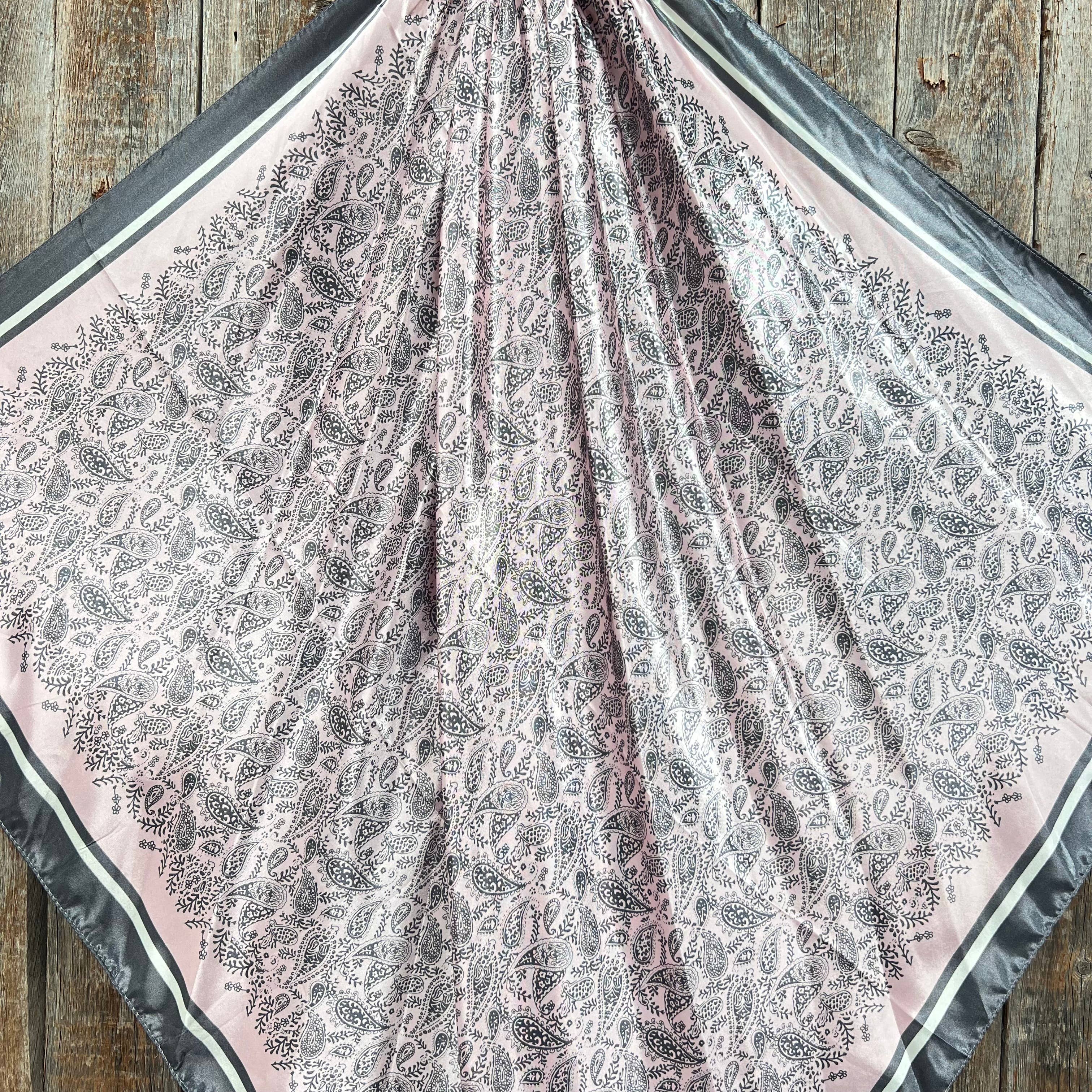 Patterned pink and grey fabric scarf on a wooden surface