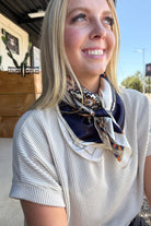 Woman wearing a patterned scarf outdoors with a clear sky.
