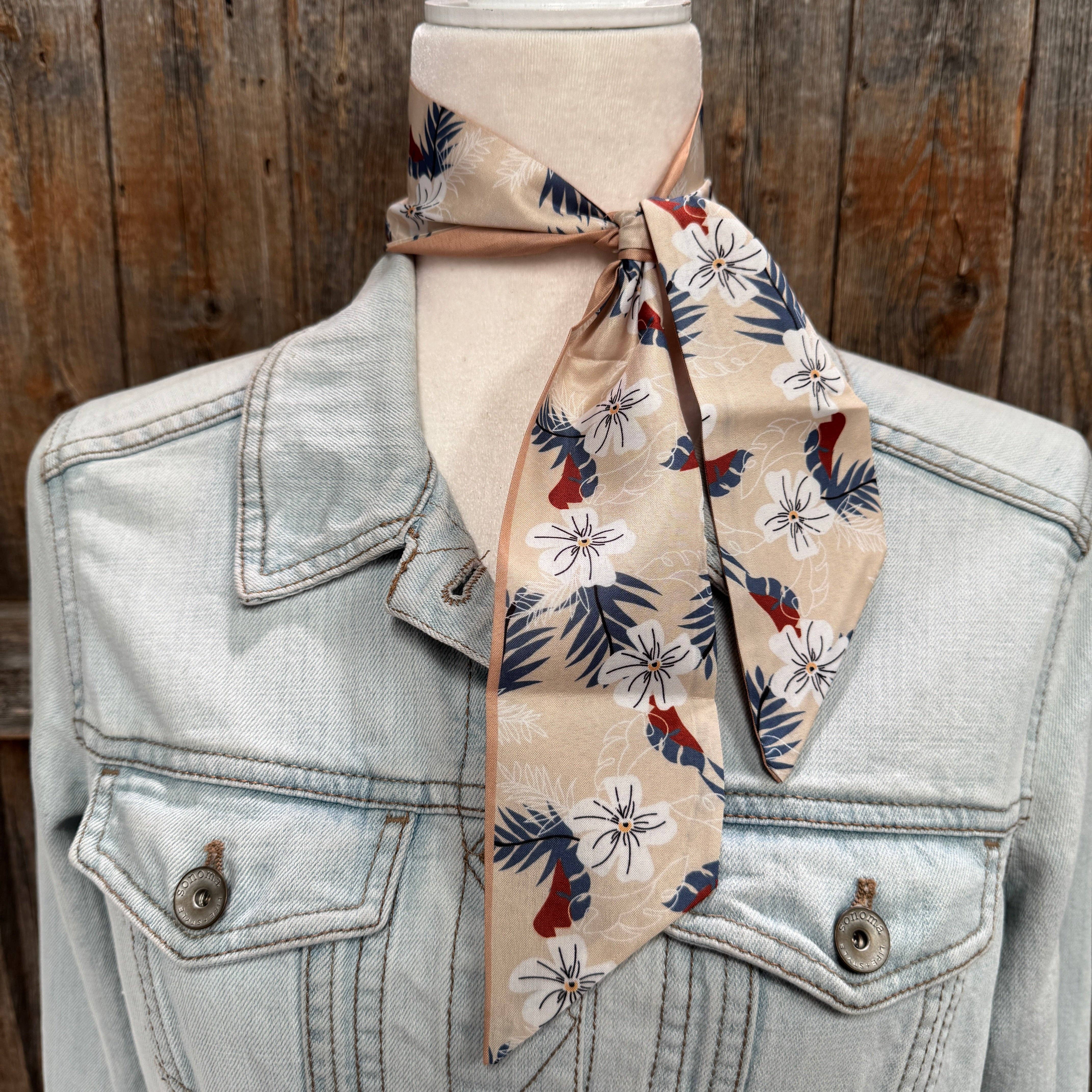 Denim jacket with a floral patterned scarf draped over it against a wooden background