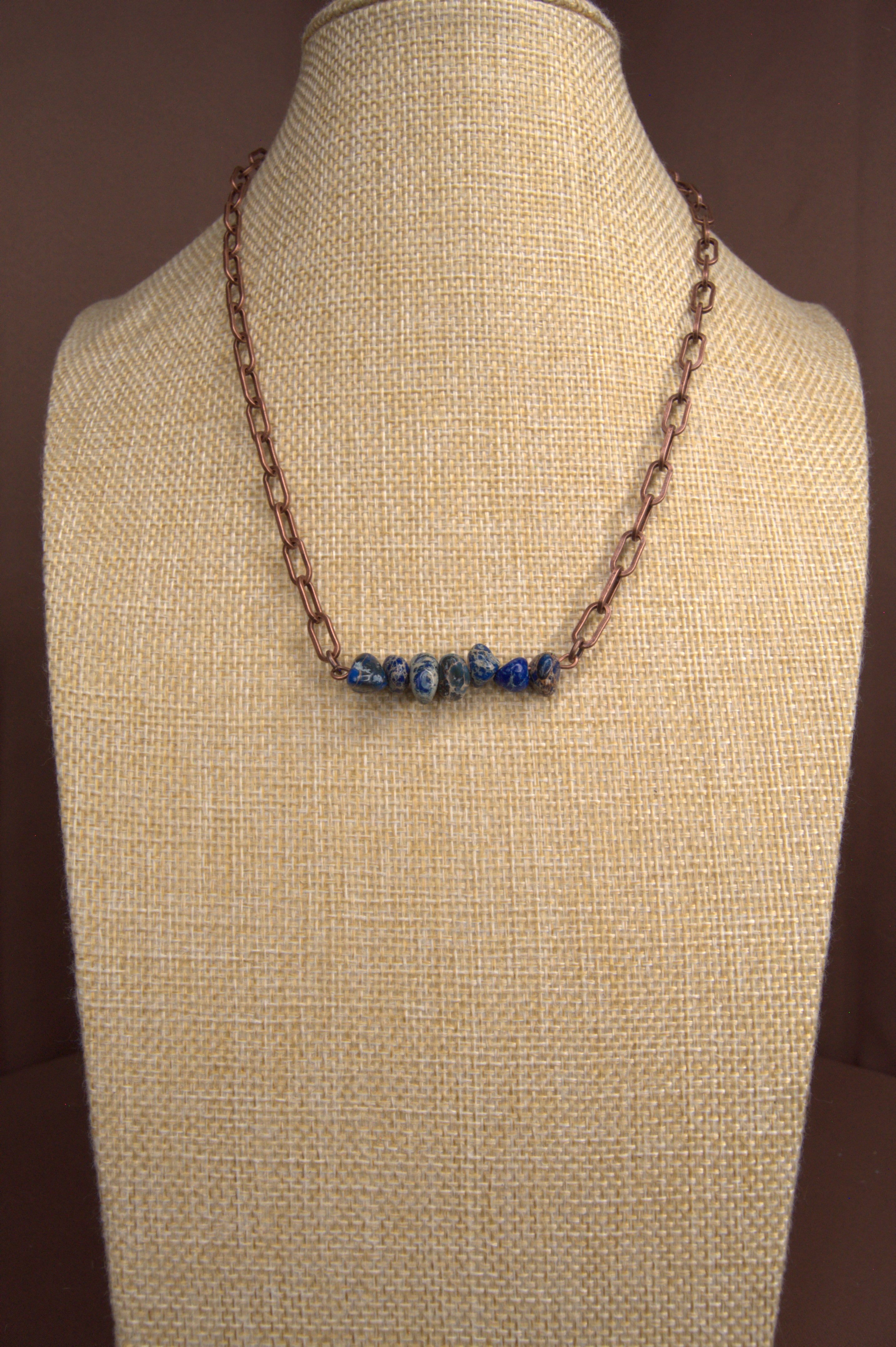 Necklace with blue chip stones  on a beige mannequin bust against a brown background